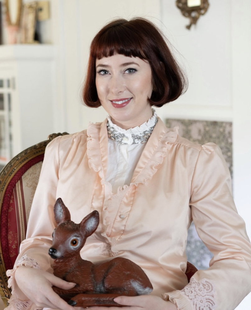Women sitting wearing pink with a small deer on her lap.